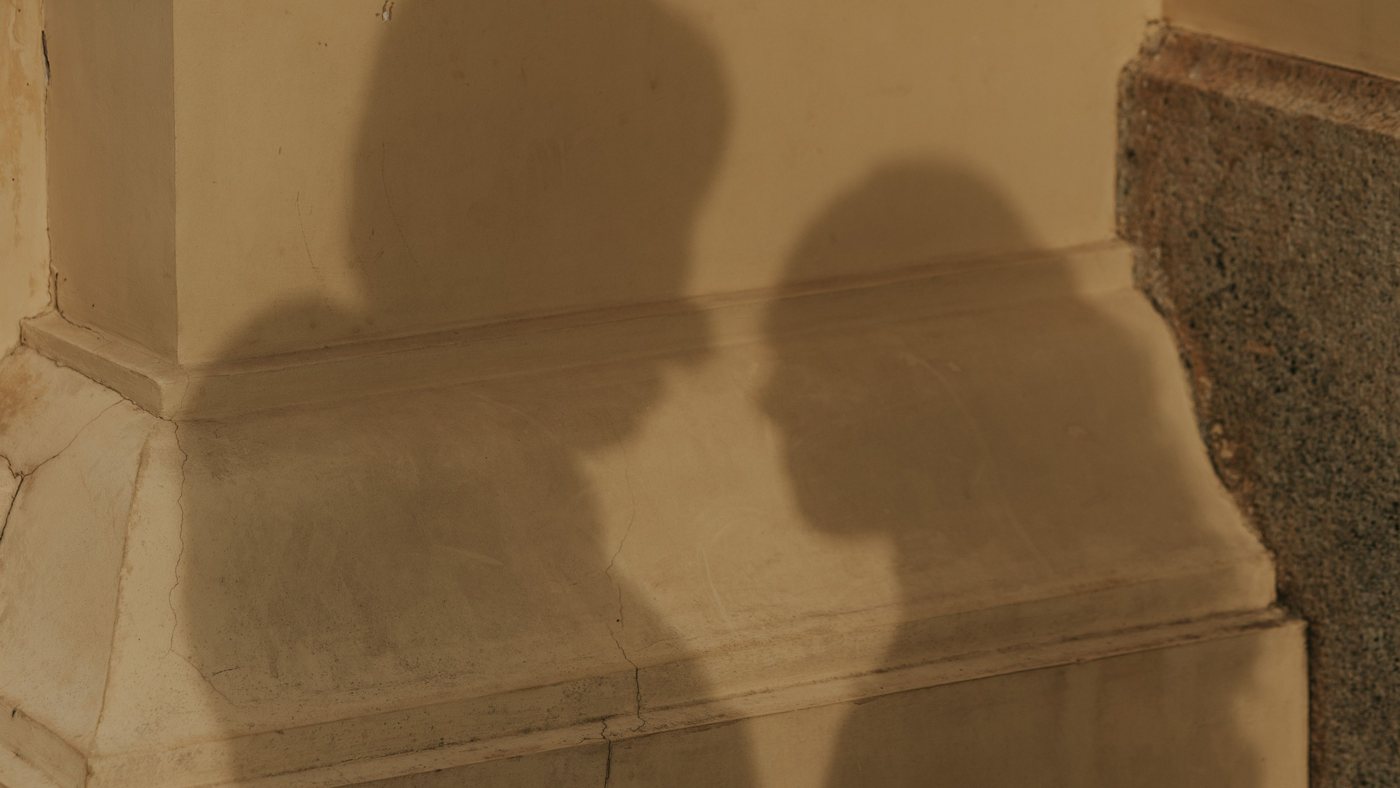 Shadows of two people facing one another on a sunlit wall