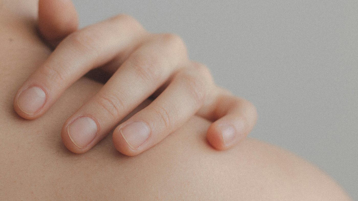 A close-up of a hand resting on a bare shoulder