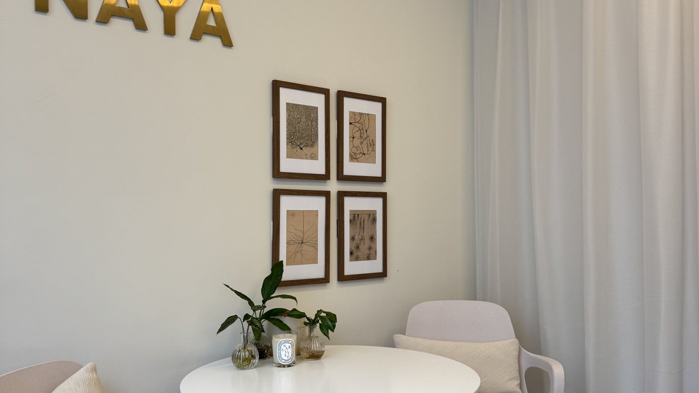 Round consultation table and chairs beneath the Naya sign at the Marylebone clinic